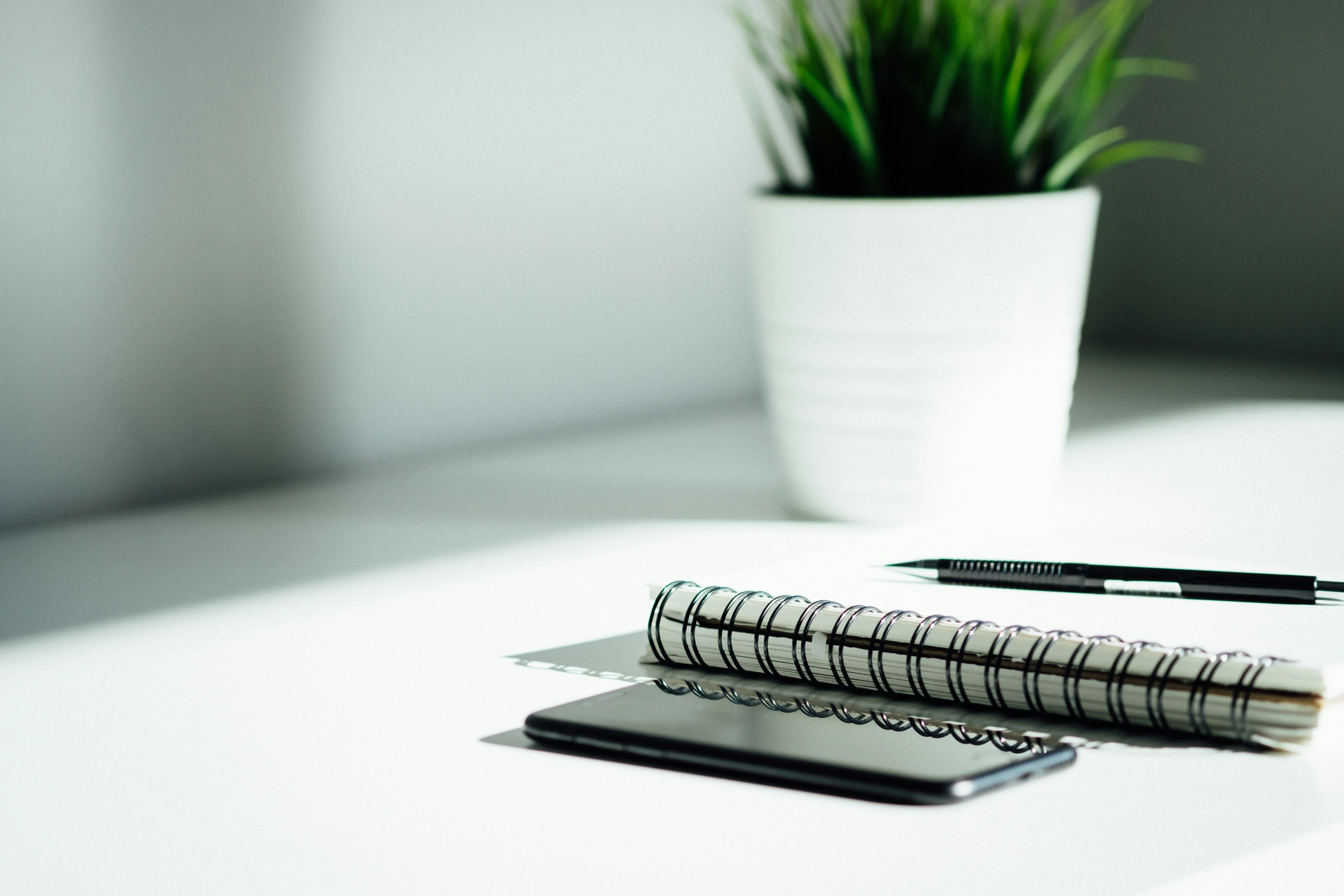 Pen, notebook, and smartphone on a clean white desk